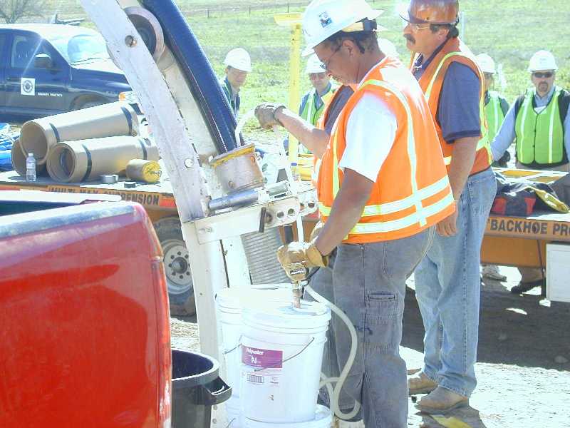 The 10-foot discharge hose is manipulated to feed lubricant directly into the conduit or onto the cable during the pull.